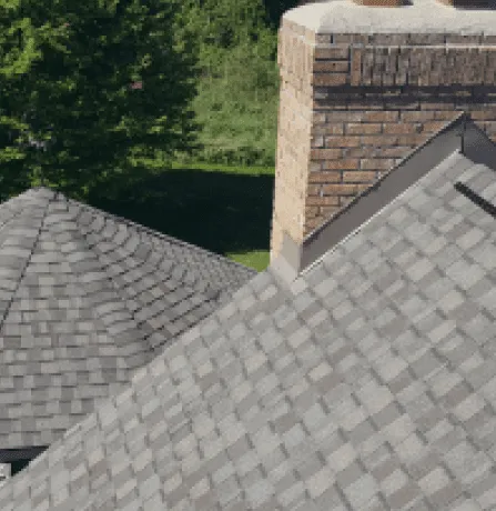 Gray asphalt shingle roof with brick chimney aerial view residential home