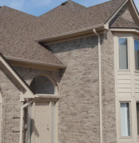 Modern brick house exterior with brown shingle roof and arched entrance