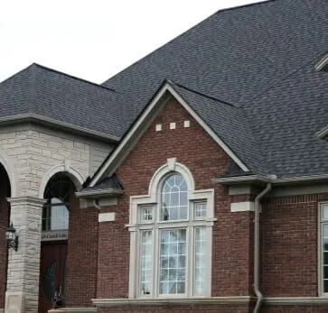 Luxury brick house with stone accents and arched windows under dark shingles