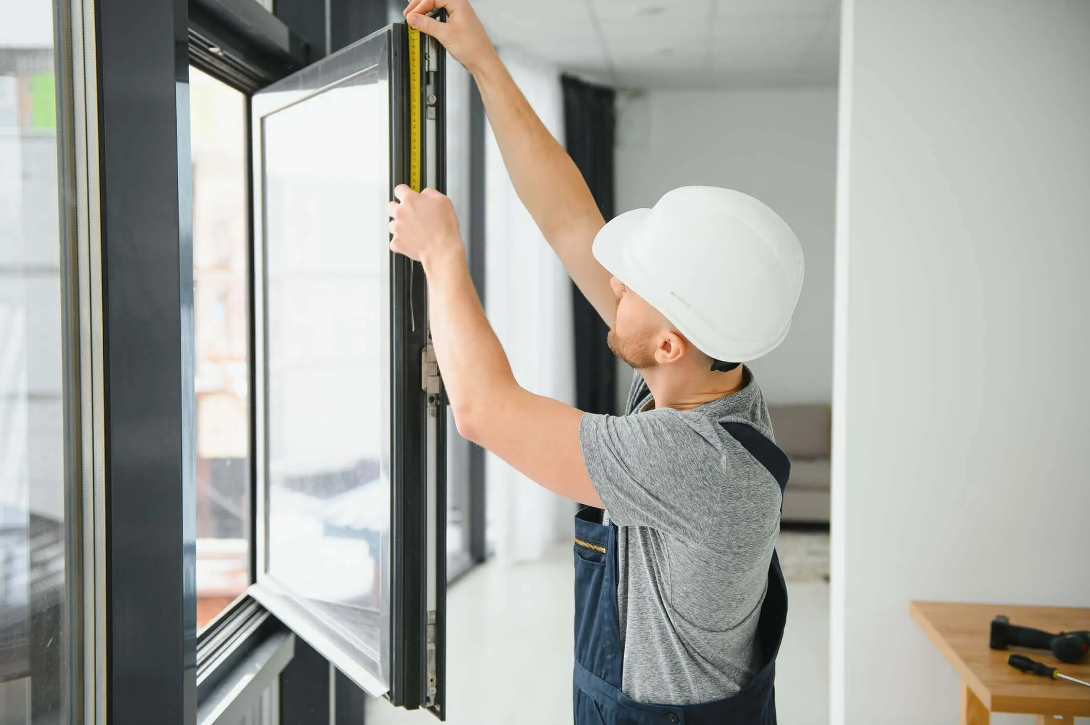 Construction worker measuring window frame for proper installation.