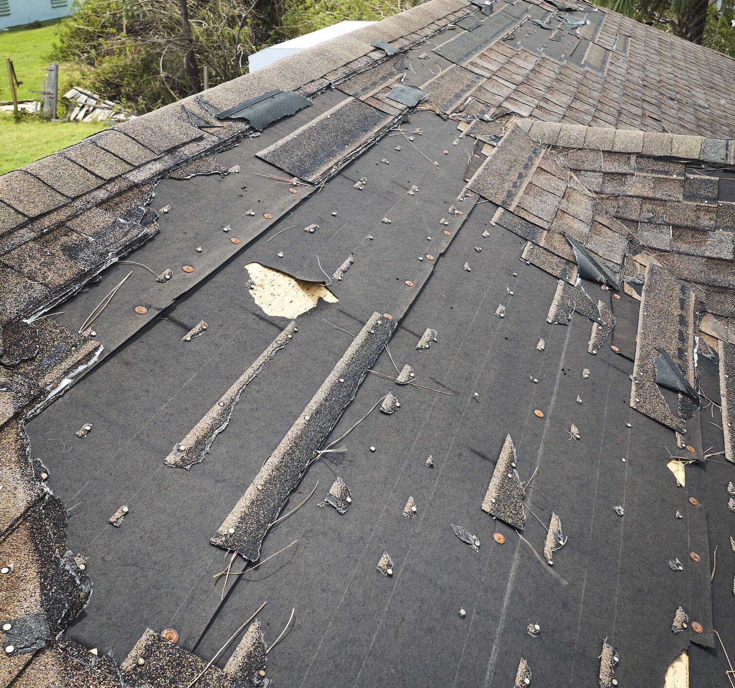 Damaged roof with torn shingles and exposed underlayment after storm damage