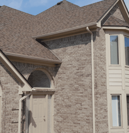 Modern brick house exterior with brown shingle roof and arched entrance