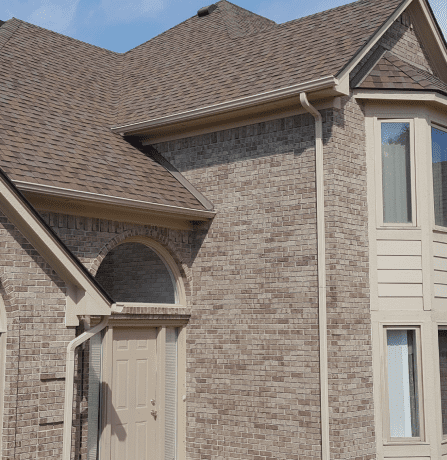 Modern brick house exterior with brown shingle roof and arched entrance