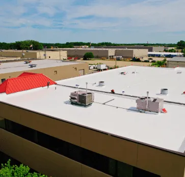Commercial building with white flat roof and HVAC units in industrial area