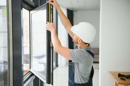 Construction worker measuring window frame for proper installation.