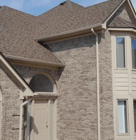 Modern brick house exterior with brown shingle roof and arched entrance