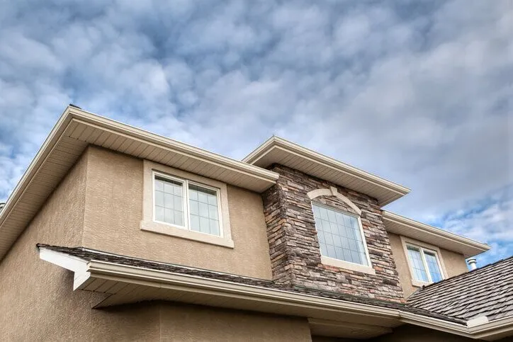 Modern suburban house with stone chimney and clear sky background.