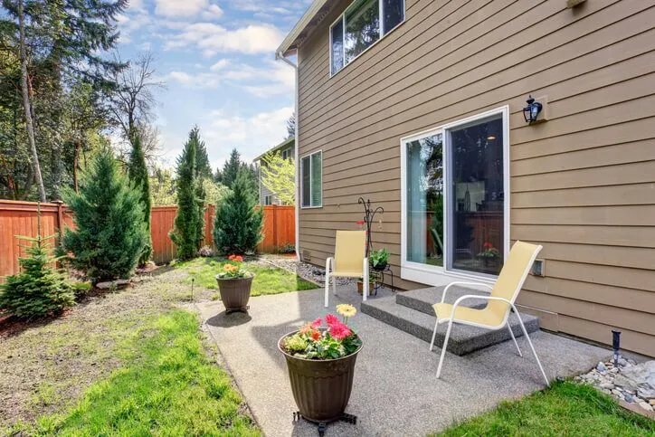 Modern backyard patio with chairs and potted plants on a sunny day
