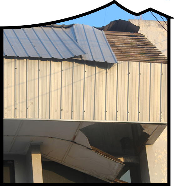 Damaged residential roof with missing metal panels and exposed wooden structure