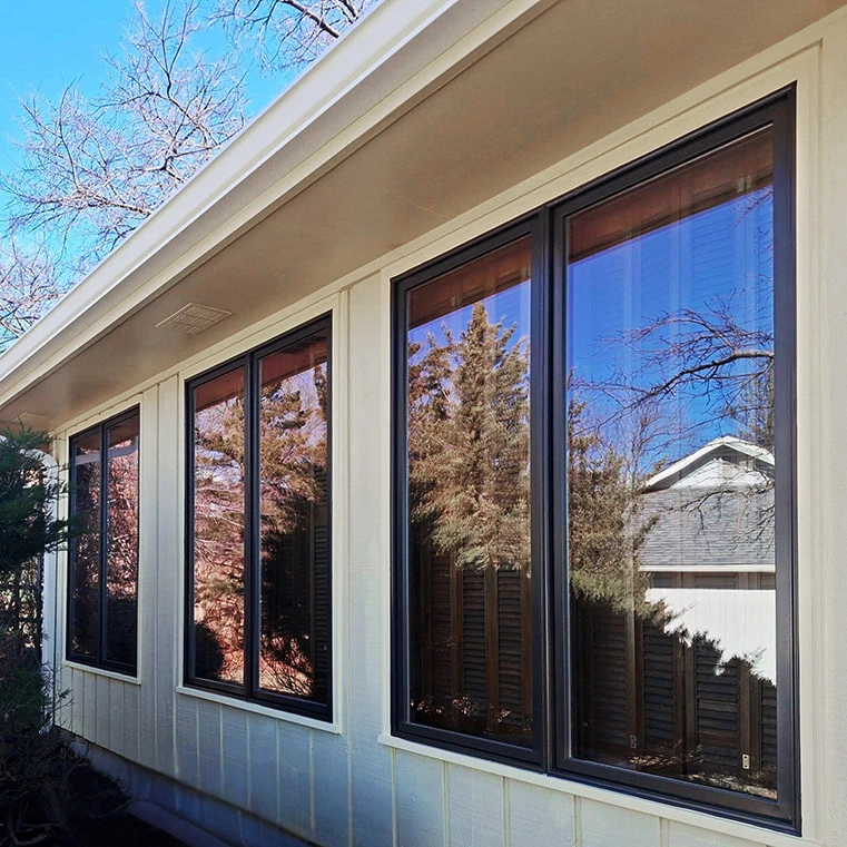 Modern home exterior with large reflective windows showing autumn trees and blue sky
