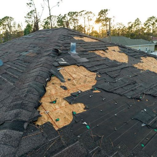 Severely damaged roof with missing shingles and exposed wood