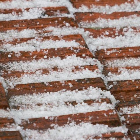 Close-up of hailstones scattered on outdoor terracotta tiles.