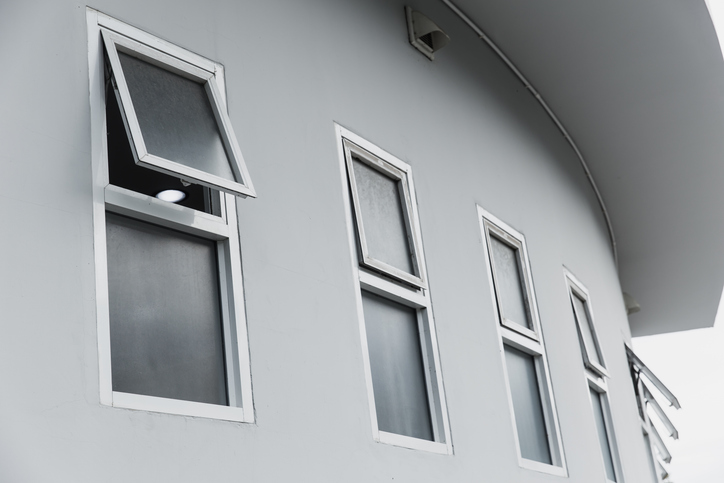 Modern building facade with multiple windows, one open for ventilation.