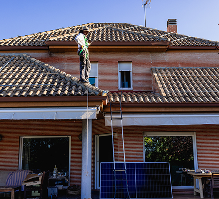 Worker installing solar panels on a residential rooftop.