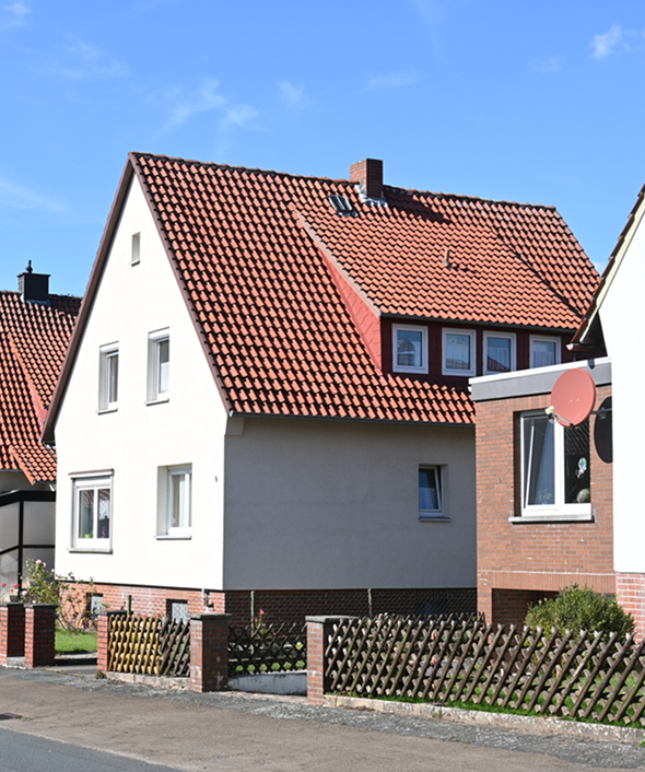 Charming suburban house with red tile roof and sunny facade.