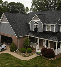 Modern two-story suburban house with a black roof and a car in the driveway.